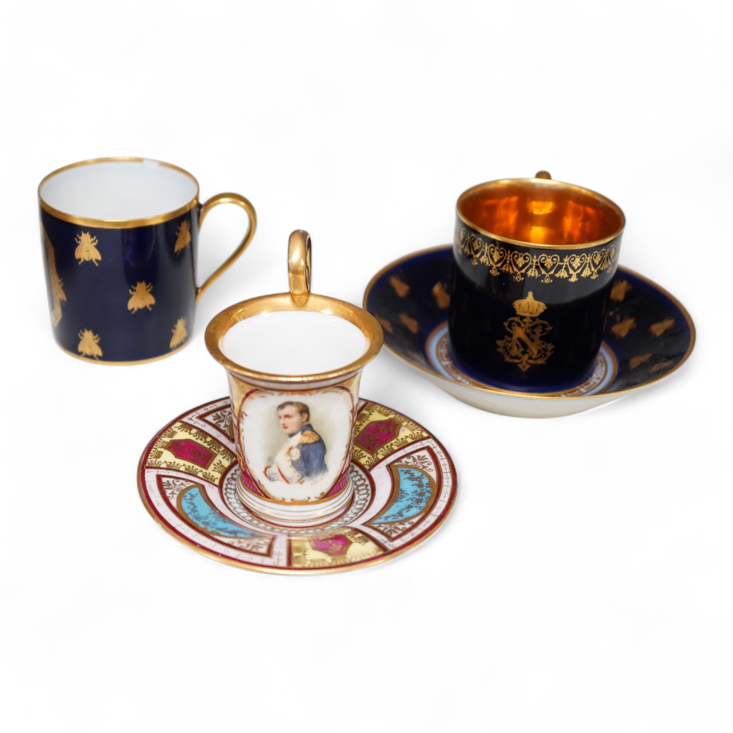 A 19th century Sevres style Napoleon cup, together with a similar cup and saucer and a Naples cup and saucer, cup 8cm from top of handle to base.